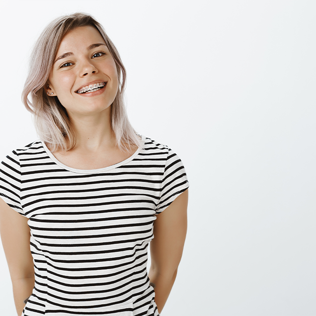 Jugendliche mit Zahnspange lächelt in die Kamera – kieferorthopädische Behandlung für gerade Zähne und ein gesundes Lächeln.