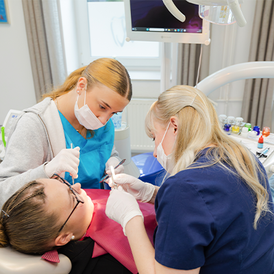 Zahnarzt und zahnärztliche Assistentin behandeln ein junges Mädchen – kinderfreundliche Zahnbehandlung und professionelle Betreuung.